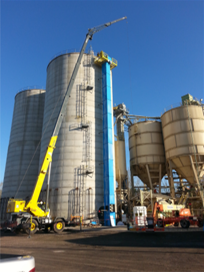 A crane is in front of some silos.